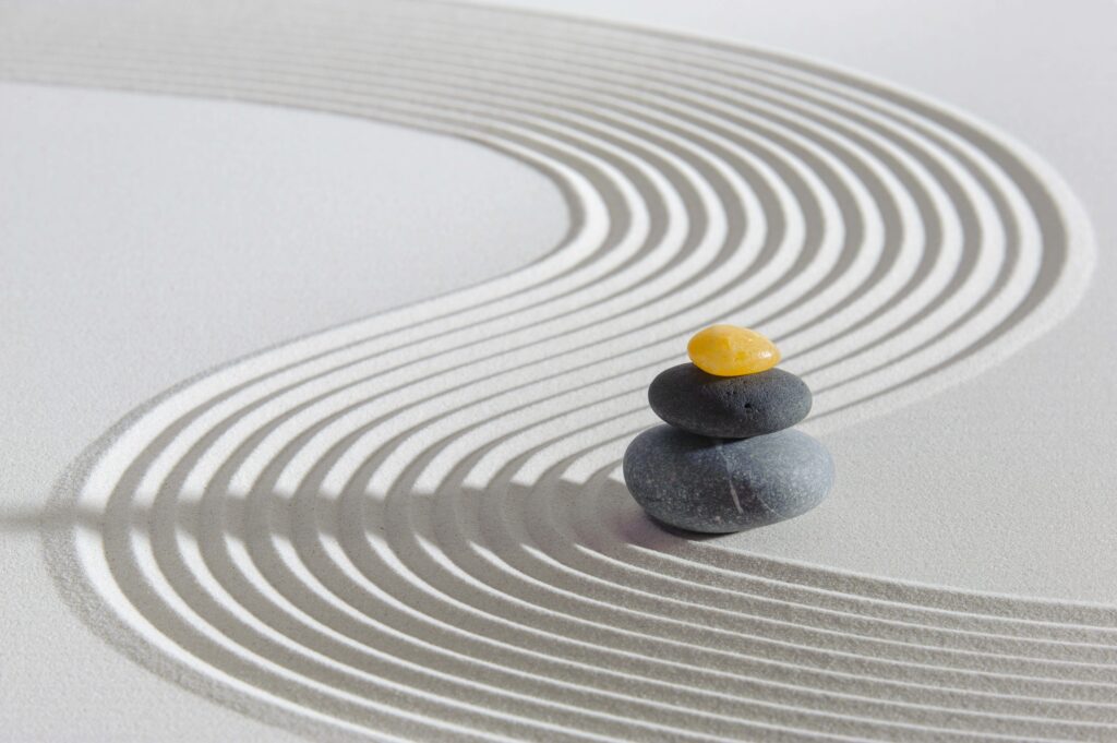 Balancing rocks with zen sand raked through depicting energy waves